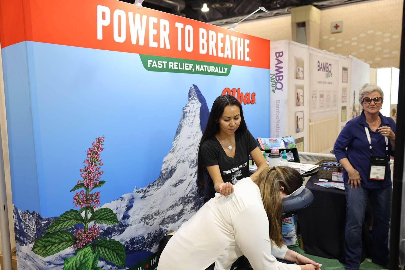Carmen enjoys a massage at olbas booth at expo east 2022