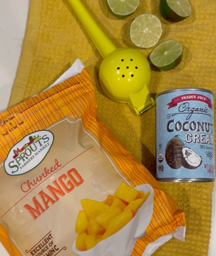 frozen mango, coconut cream, and limes laid out on a table