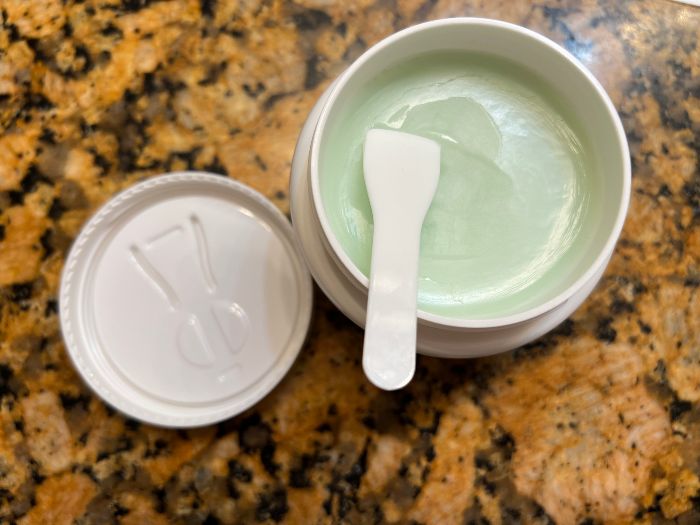 A jar of green balm with a spatula